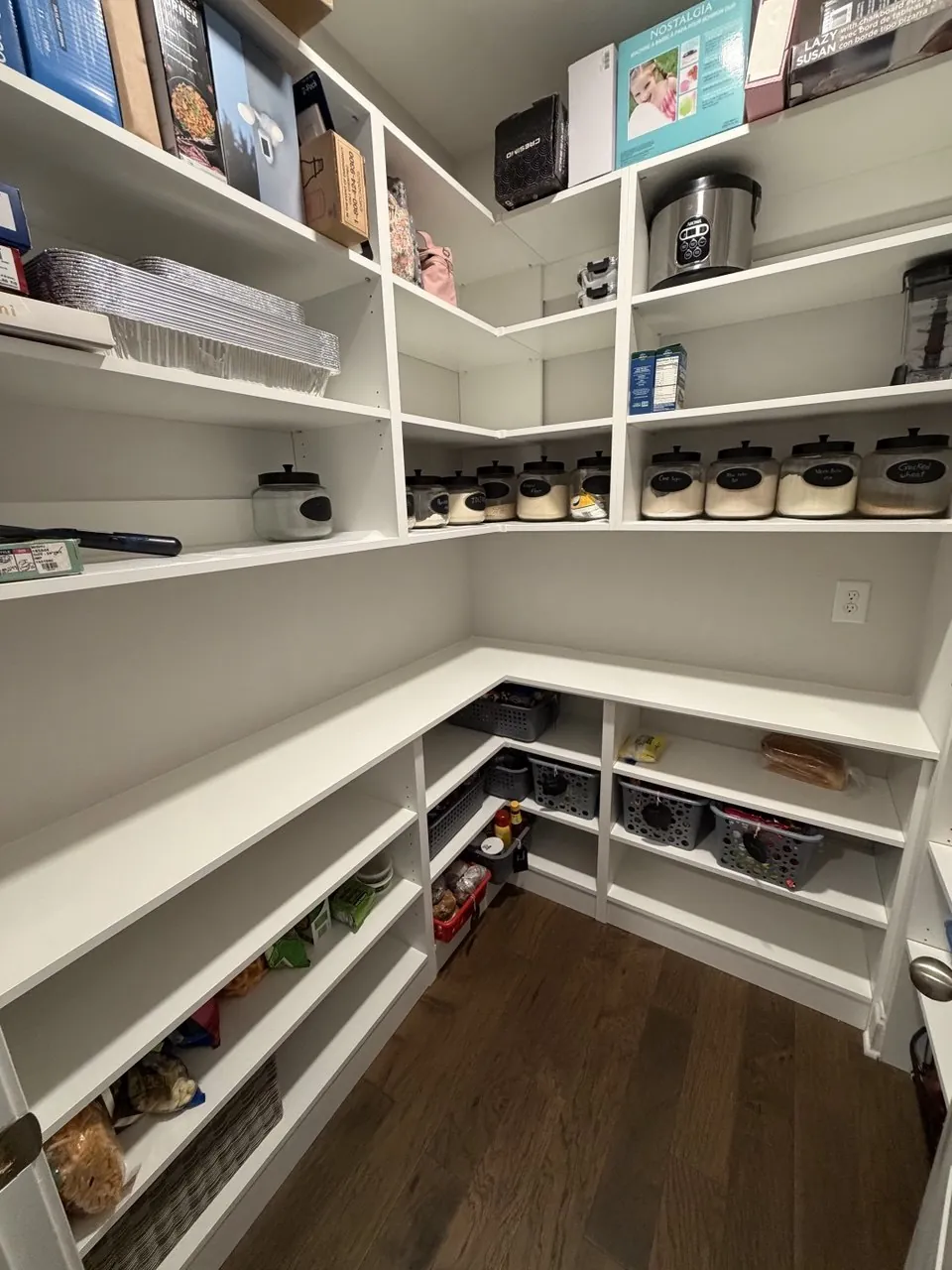 Walk-in pantry with white corner shelving, stocked jars and pull-out baskets in an Atlanta kitchen