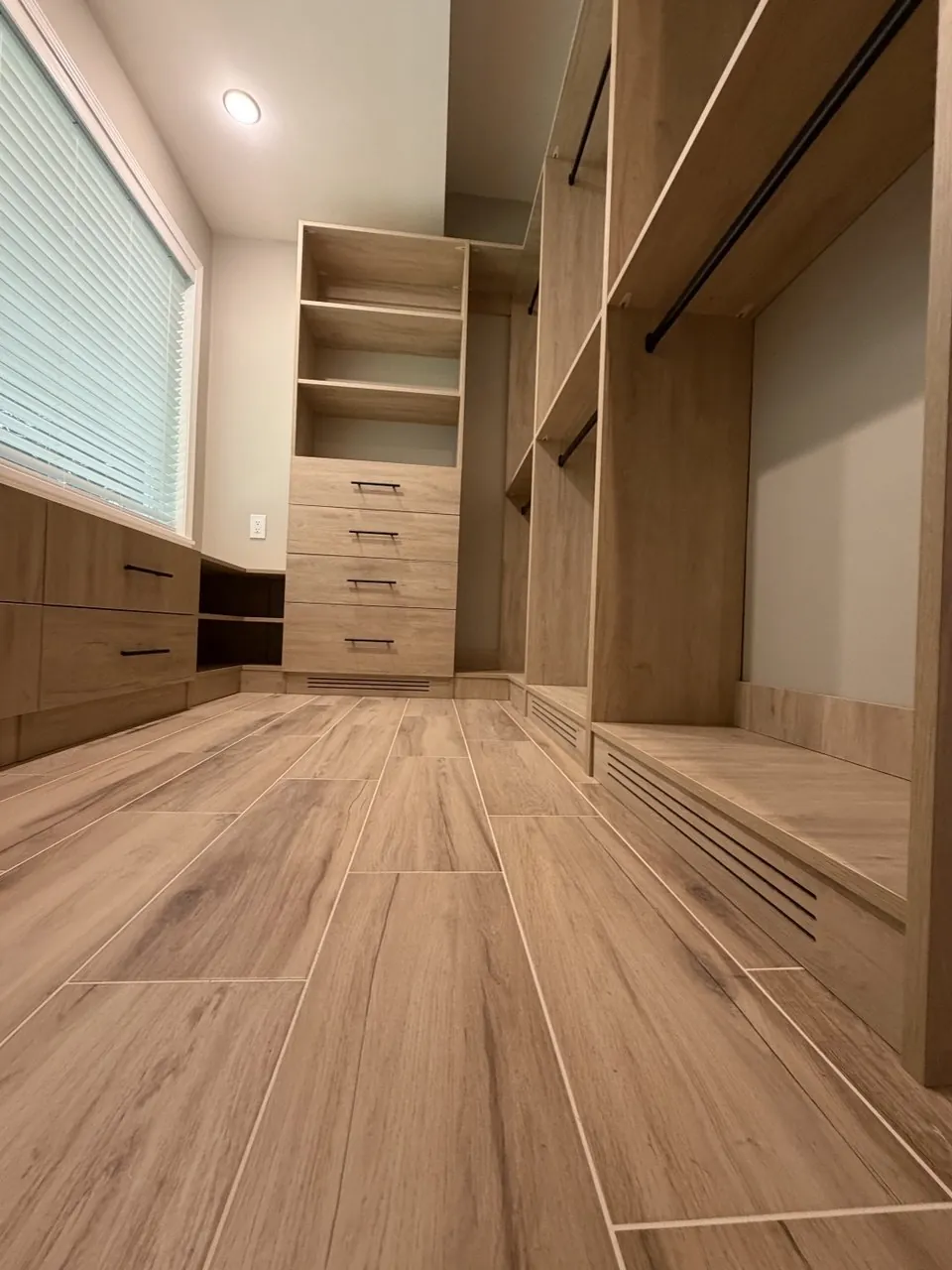 Oak walk-in closet with double hanging and wood-look tile flooring
